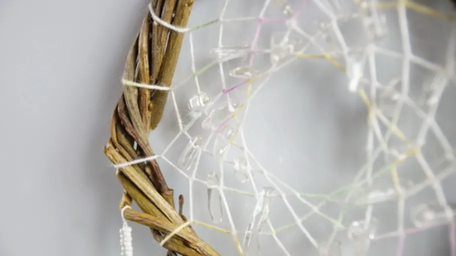 photo of a dreamcatcher made by hand, with using threads, beads and feathers from different birds
