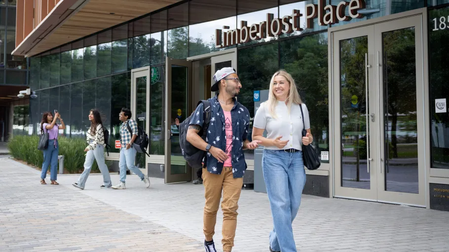 Two students walk and chat outside of the Limberlost Place entrance