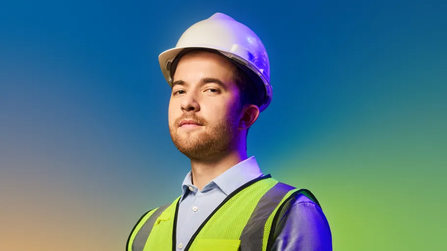 A man in a hard hat and high vis vest stands against a colourful blue gradient