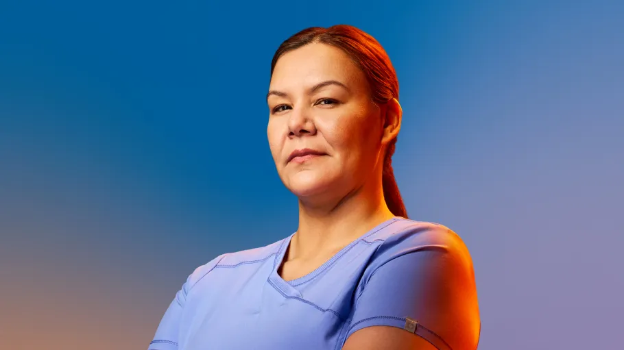 A woman in scrubs stands against a colourful blue gradient
