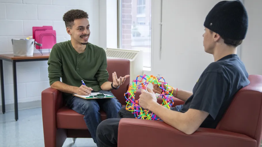 Two people having a conversation. One is taking notes and the second one is playing with a jumbo expand-a-ball