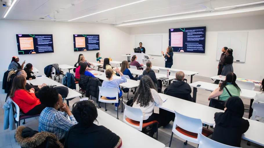 Mental Health Conference participants in a workshop room with digital screens and a presenter