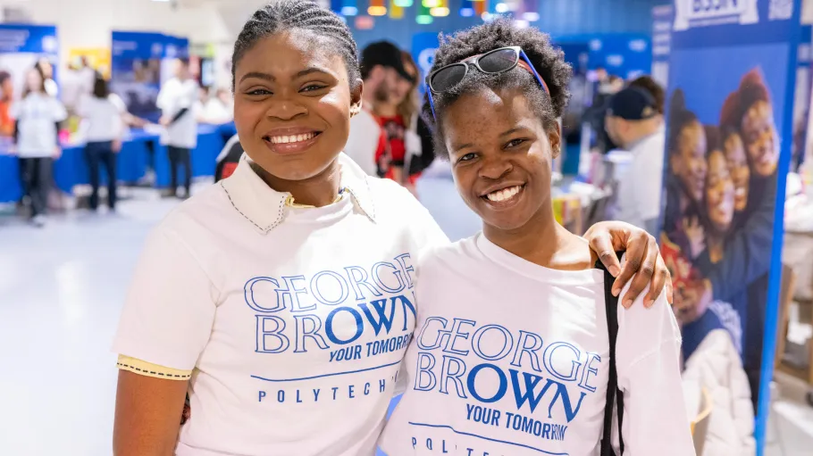 Two student volunteers at the spring open house smile
