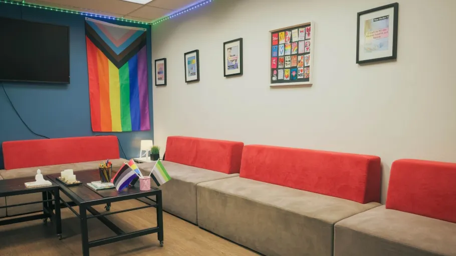 A picture of the interior of the Calm Zone, featuring benches, a Pride flag, and wall art.