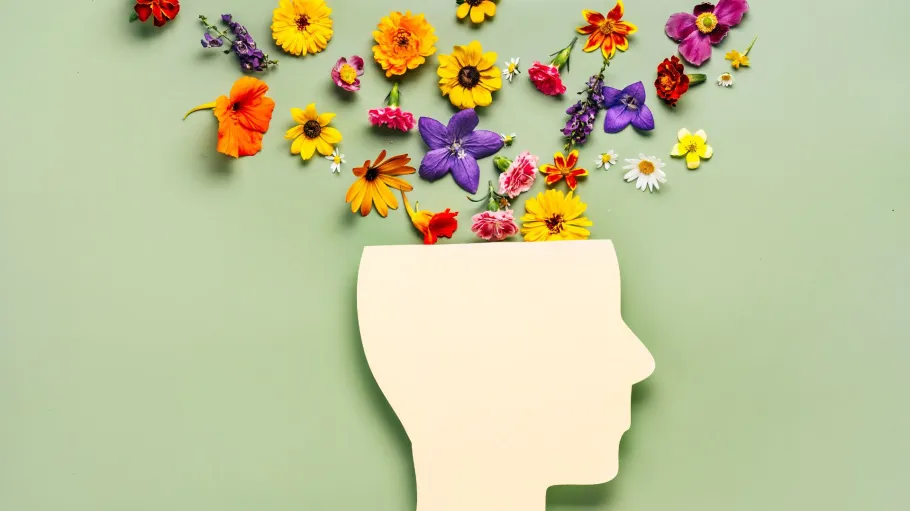 A photo of a paper silhouette of a head, with flowers laid from the head to the top of the photo.