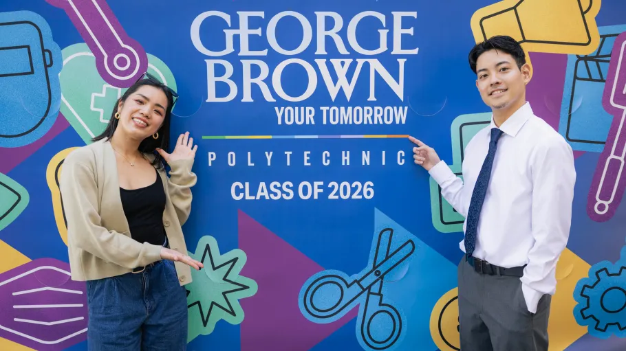 Grads pose at the 2026 convocation mural at Meridian Hall.