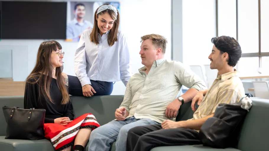 A group of four students chat in a common space on campus.