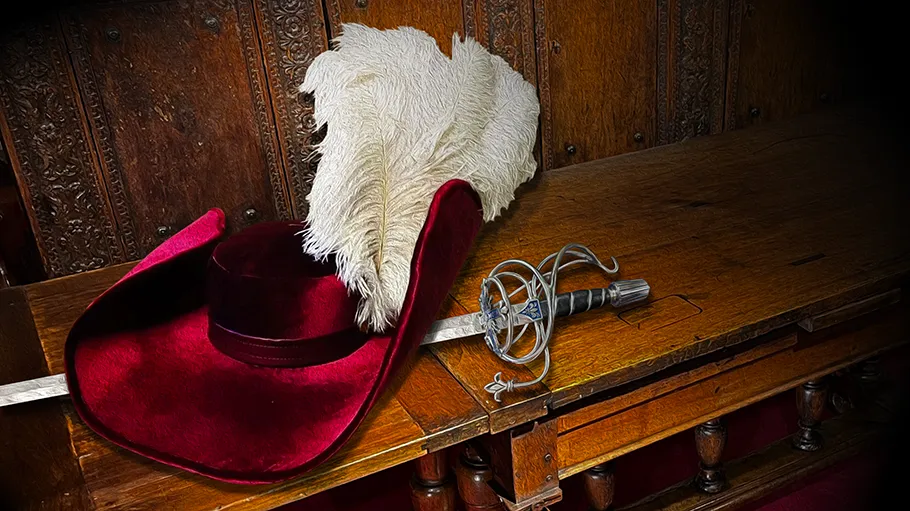 Elizabethan era clothing and a sword lie draped across a wooden bench