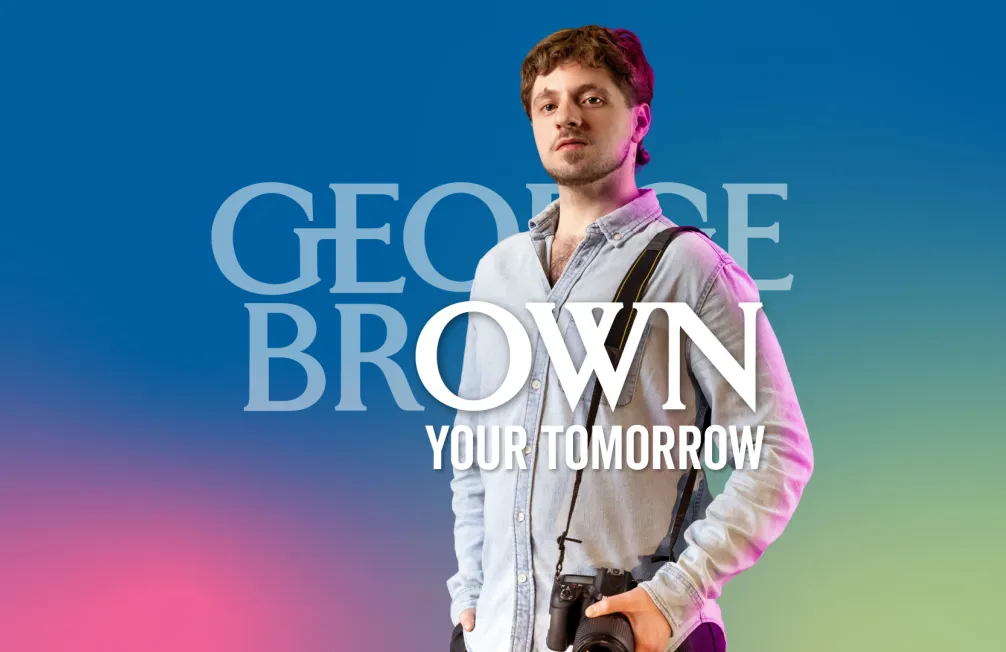 A student in a denim shirt and a camera over his shoulder stands in front a colourful blue gradient with the words "George Brown Your Tomorrow" in front of him.