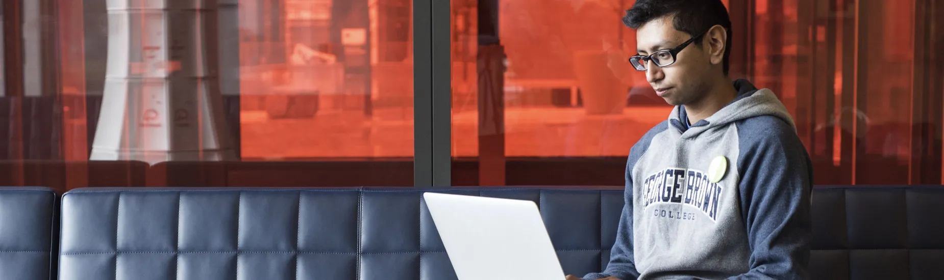 Student sitting on couch, using a laptop