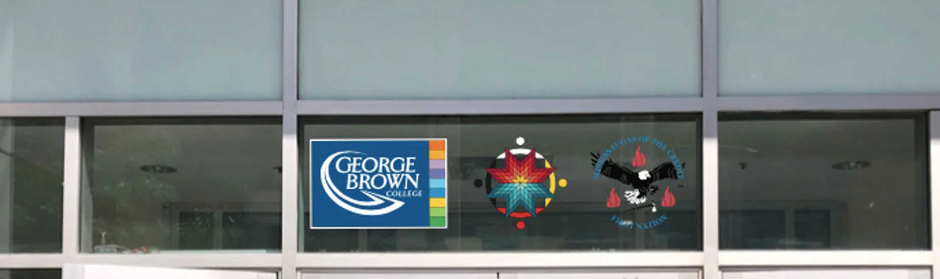The crest of the Mississaugas of the Credit First Nation, along with the medallion of our Indigenous Initiatives team, proudly displayed next to the George Brown College logo above a campus doorway.