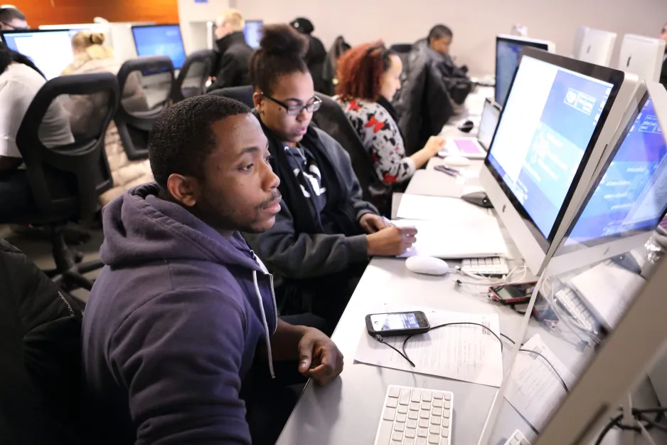Students working in the library on the computers together. Group working environment.