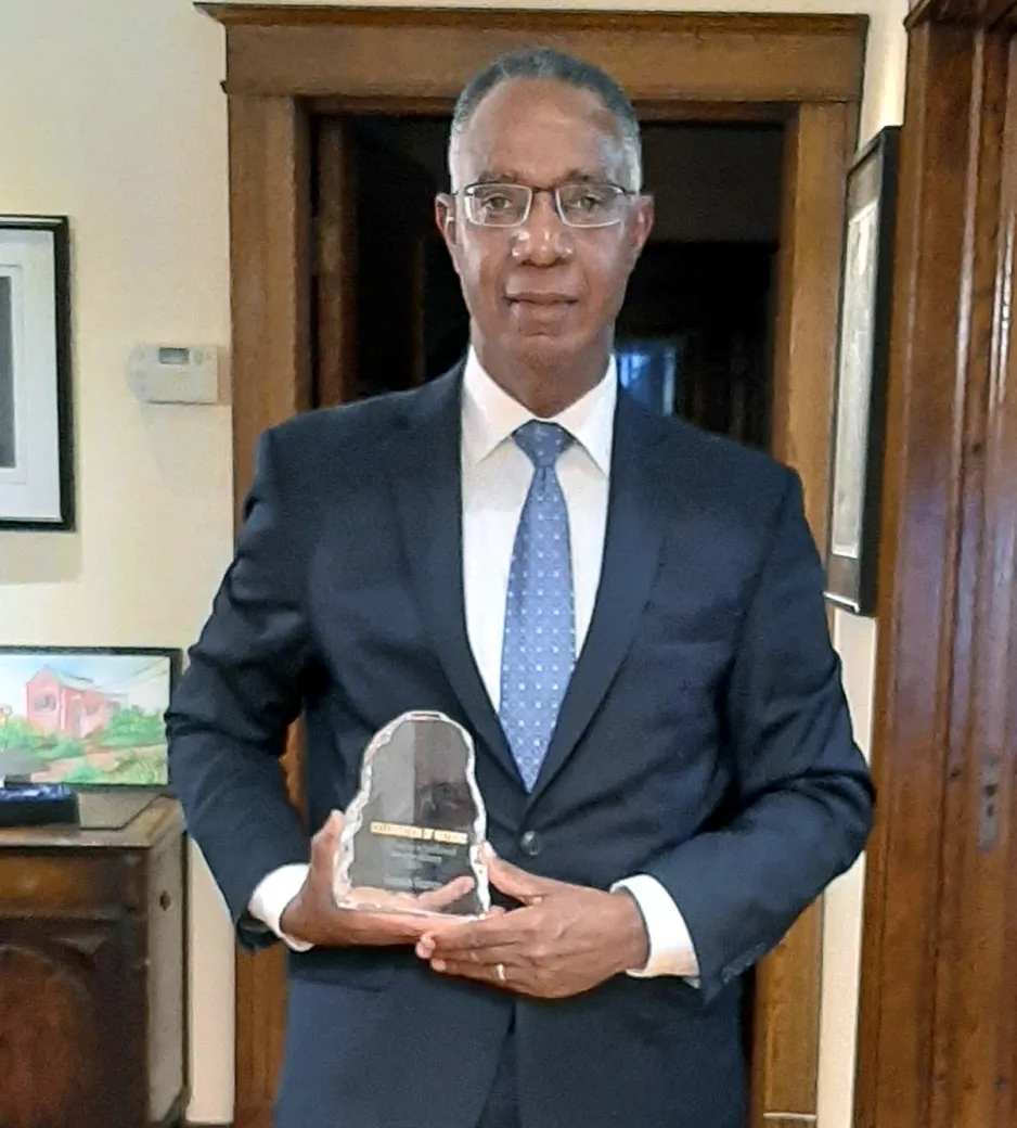 Dr. Gervan Fearon holding Celebration of Nations award