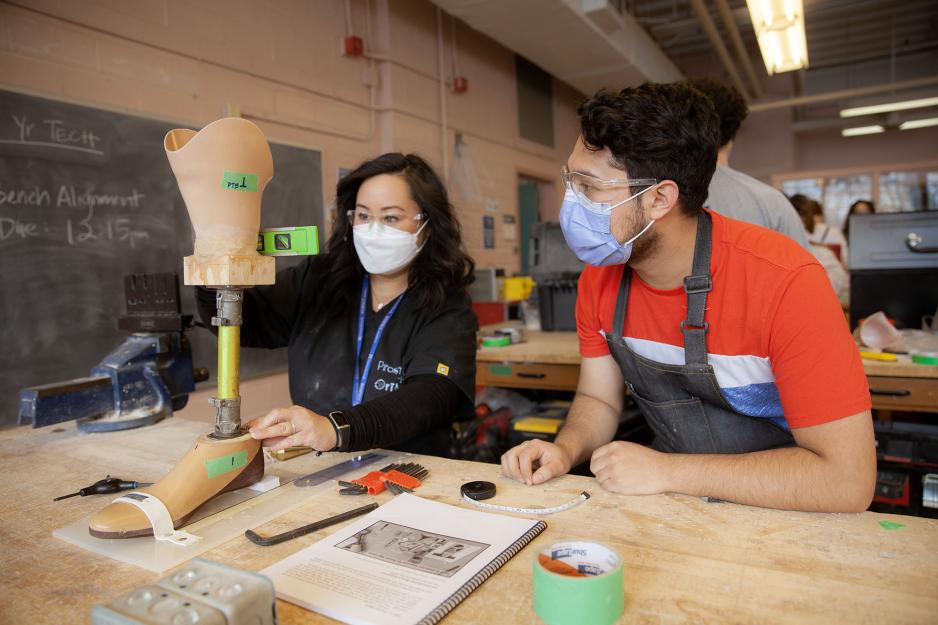 Faculty advises a male Orthotic/Prosthetic Technician (S102) student in the lab as he designs a prosthetic limb.
