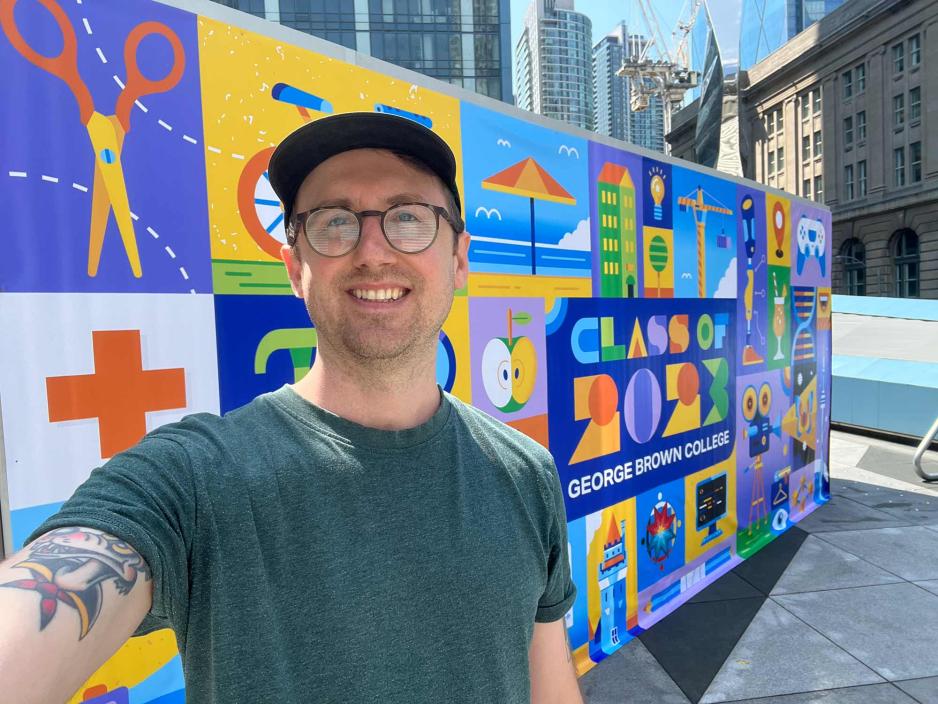 Graphic Design grad Ben O'Neil in front of his convocation mural