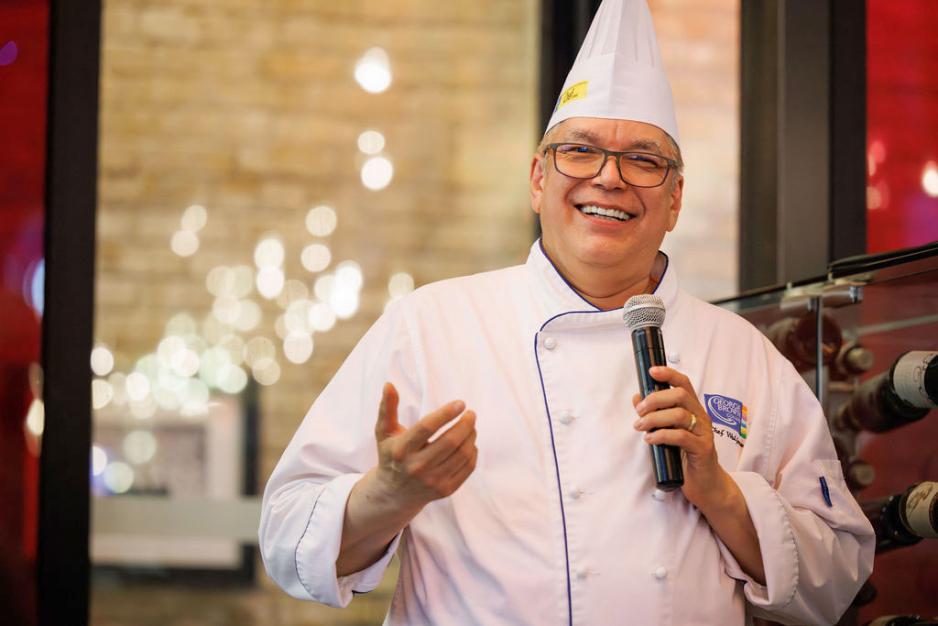 Chef David Wolfman smiling and holding a microphone