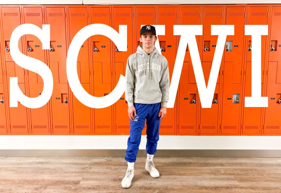MJ Given standing in front of a bank of lockers with SWCI letters in the background.