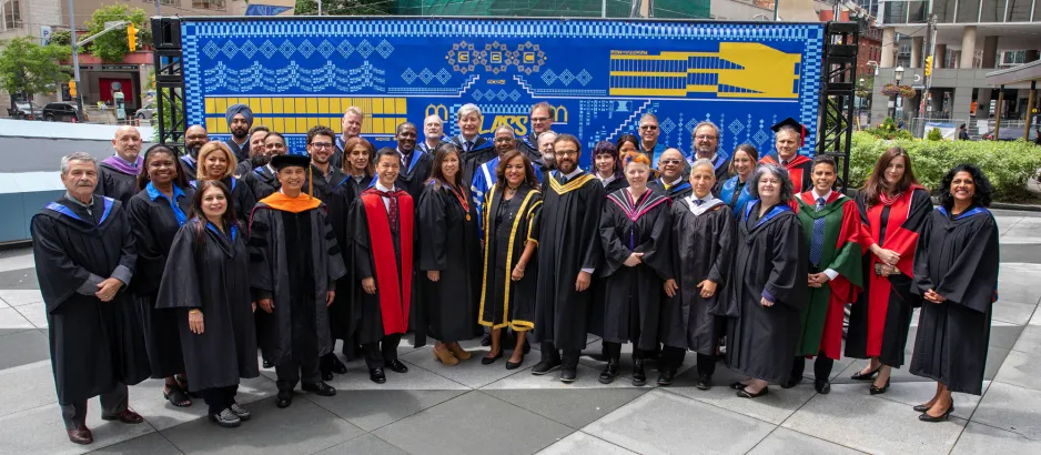 Faculty, employees and college leaders in front of Ben Luu's mural at Convocation