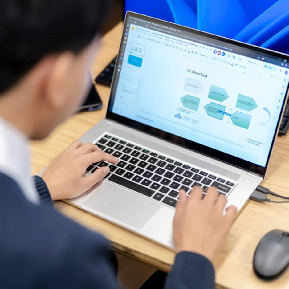 Viewing over the shoulder of a student working on a user experience chart on a laptop screen