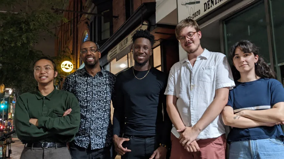 Band members of The Shop pose outside on a dark evening