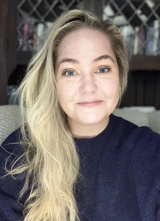 A woman with blonde hair and a black shirt, smiling
