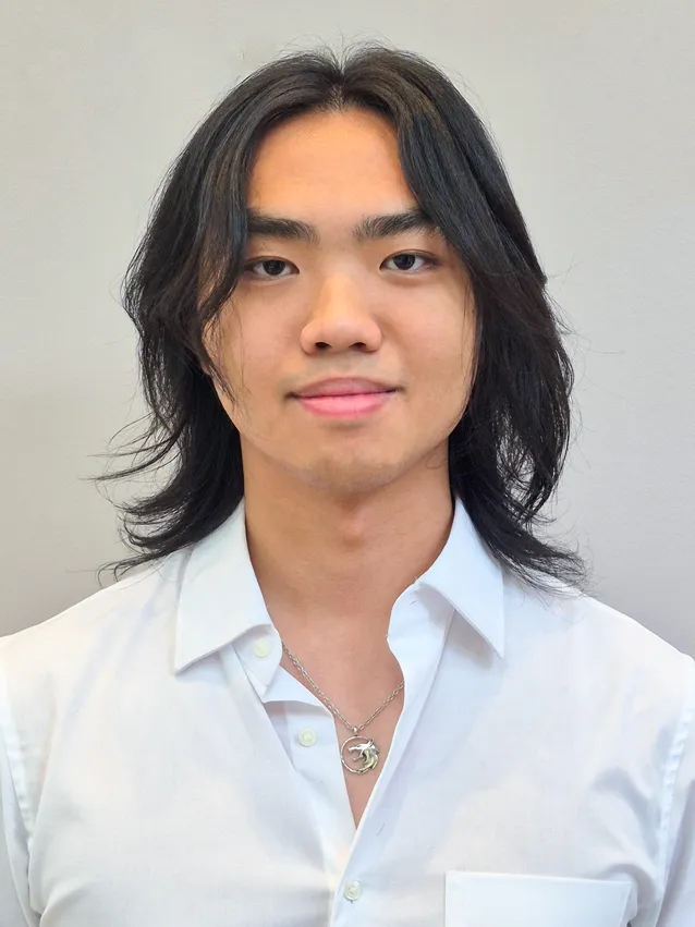 A headshot of Justin Purnoko who has shoulder length black hair and wears a white collared shirt