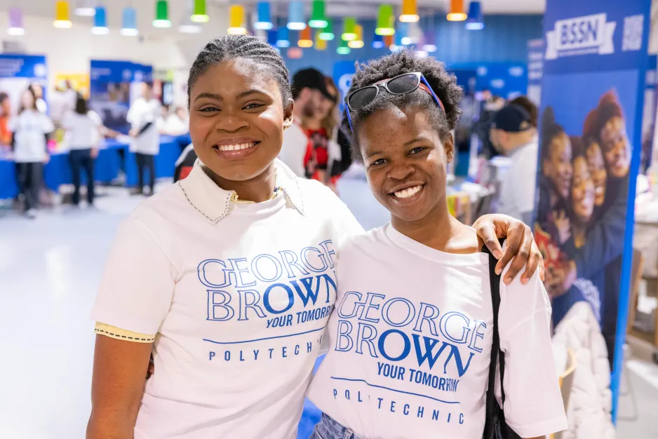 Two student volunteers at the spring open house smile