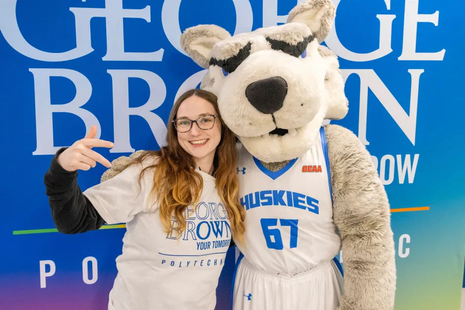 A student poses with George Brown's mascot, Helder