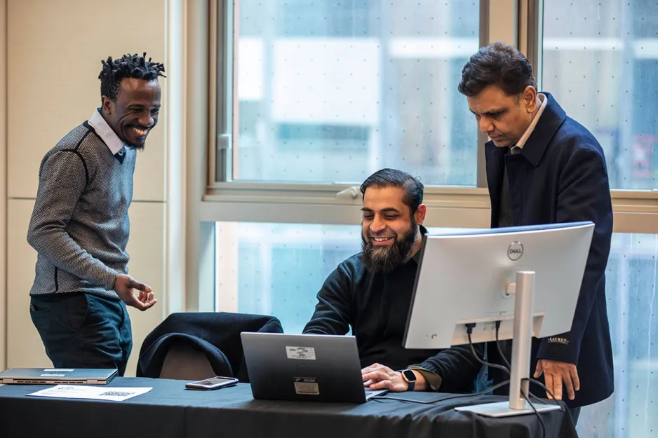 3 people smiling around computer