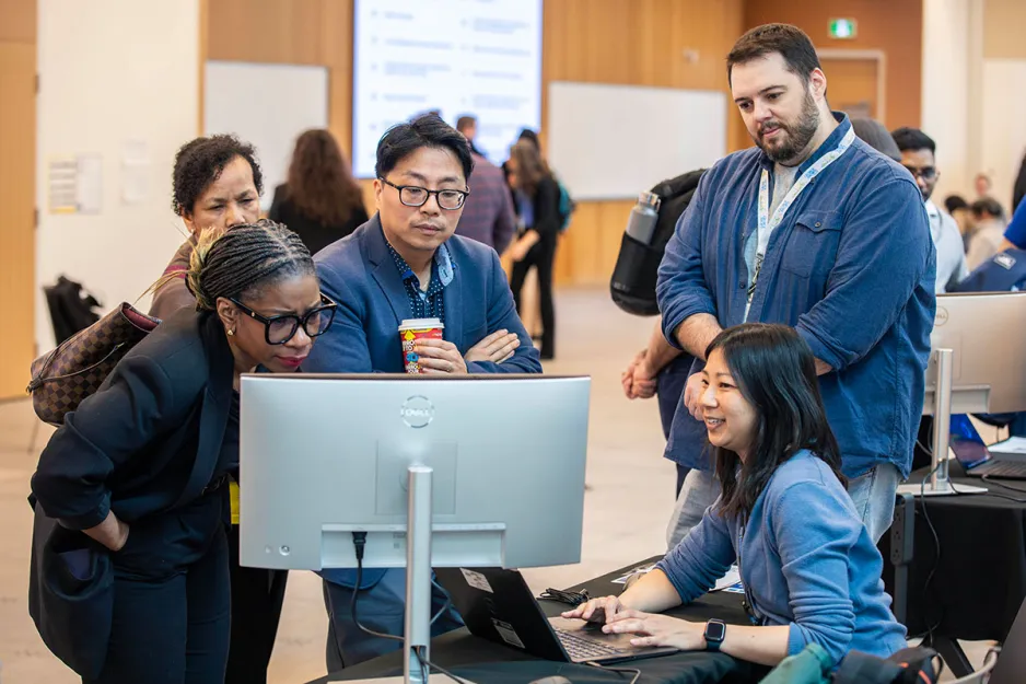 5 people standing around a computer