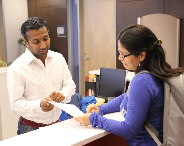 A student asks a question to one of the employees at a welcome desk.