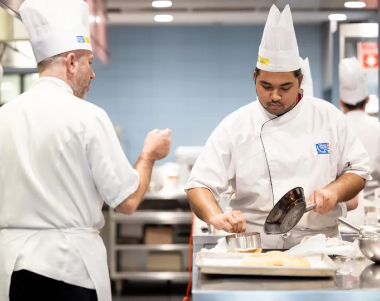 A chef instructor supervises and offers advice, as student chefs work in the Chef School industrial kitchens at the Centre for Hospitality and Culinary Arts, St. James campus.