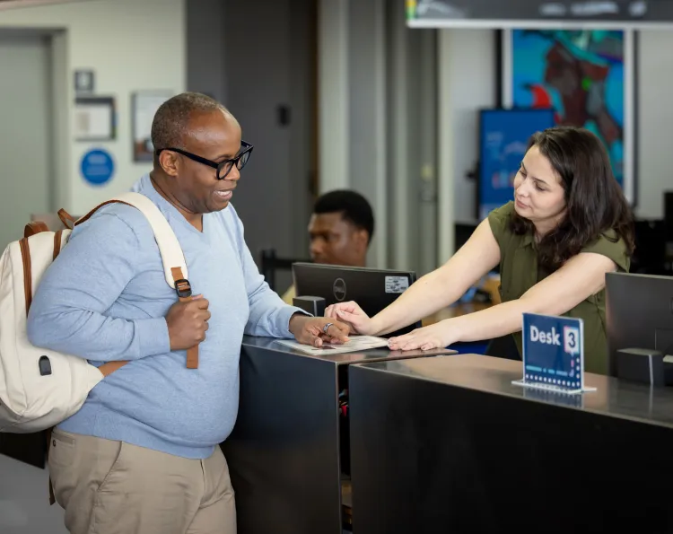A student receiving help from a library employee at the service desk