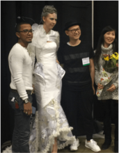 Designers posing with model wearing white dress.