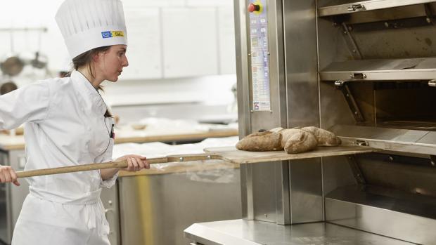 Student putting dough in oven