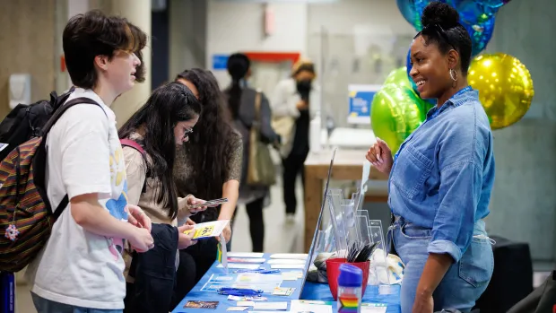 A student speaks with a volunteer at a campus fair