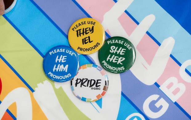 Colourful pronoun buttons are laid against a colourful background