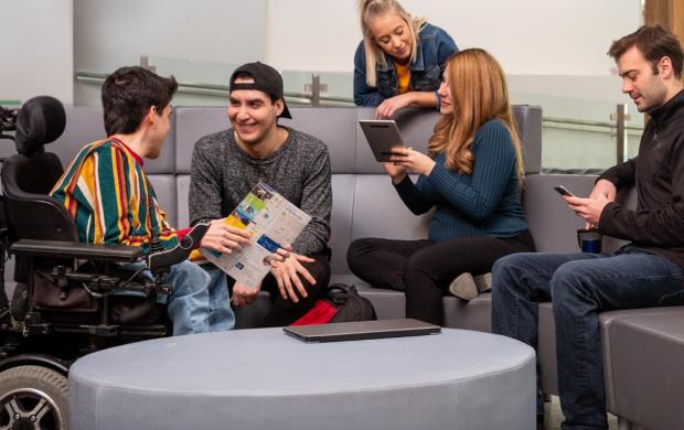 a student in a wheelchair conversing with other students in a GBP lounge area
