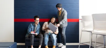 3 students looking at a laptop
