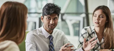 CHCA students sitting around a table full of papers talking. 