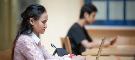 Female student using a laptop with another student in background