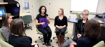 American Sign Language - English Interpreter teachers and students seated in circle in classroom having a discussion (in ASL).
