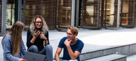 Three students sitting on steps outside talking.