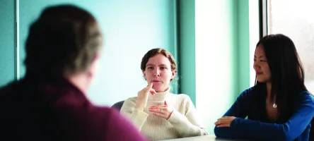 Anna Lee, American Sign Language (ASL) - English Interpreter Program graduate, sits at a table while interpreting with others.