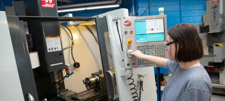 CCET Female student in a lab operating a Haas machine.