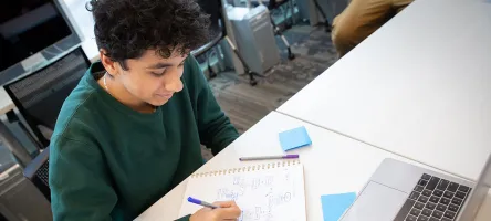 male student writing in notebook