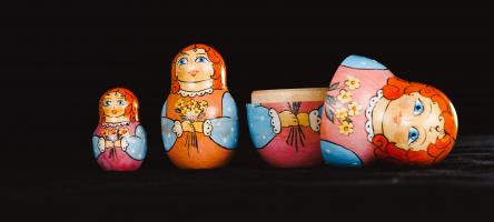 Set of three Russian dolls with the largest one open and the lid laying on its side.