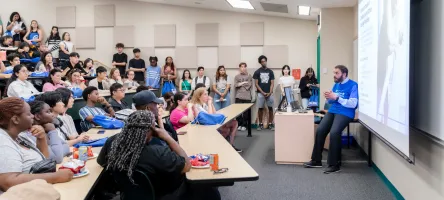 Students sit in a classroom for a program orientation, listening to the Dean.