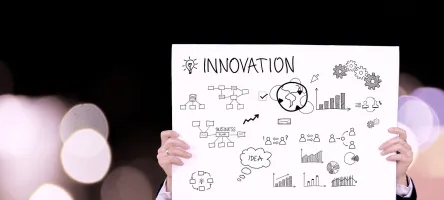 Person holding a poster with the word "Innovation" and sketches of ideas, charts, and gears.