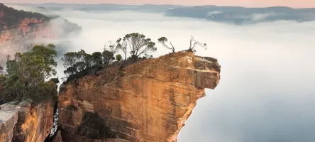 Seen from above, Hanging Rock in Australia can be seen in the distance with clouds in the background.